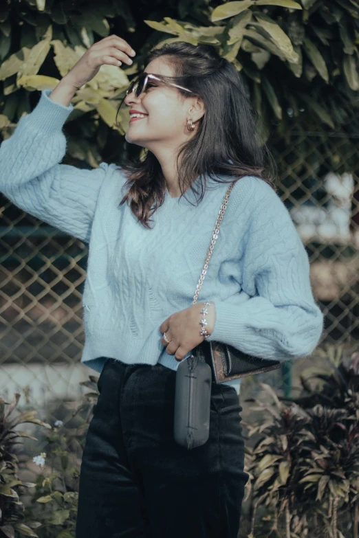 a woman wearing black pants and a blue sweater is posing