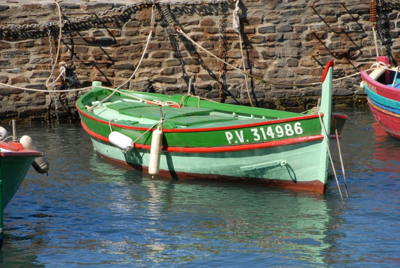 four boats are docked on the water in front of a wall