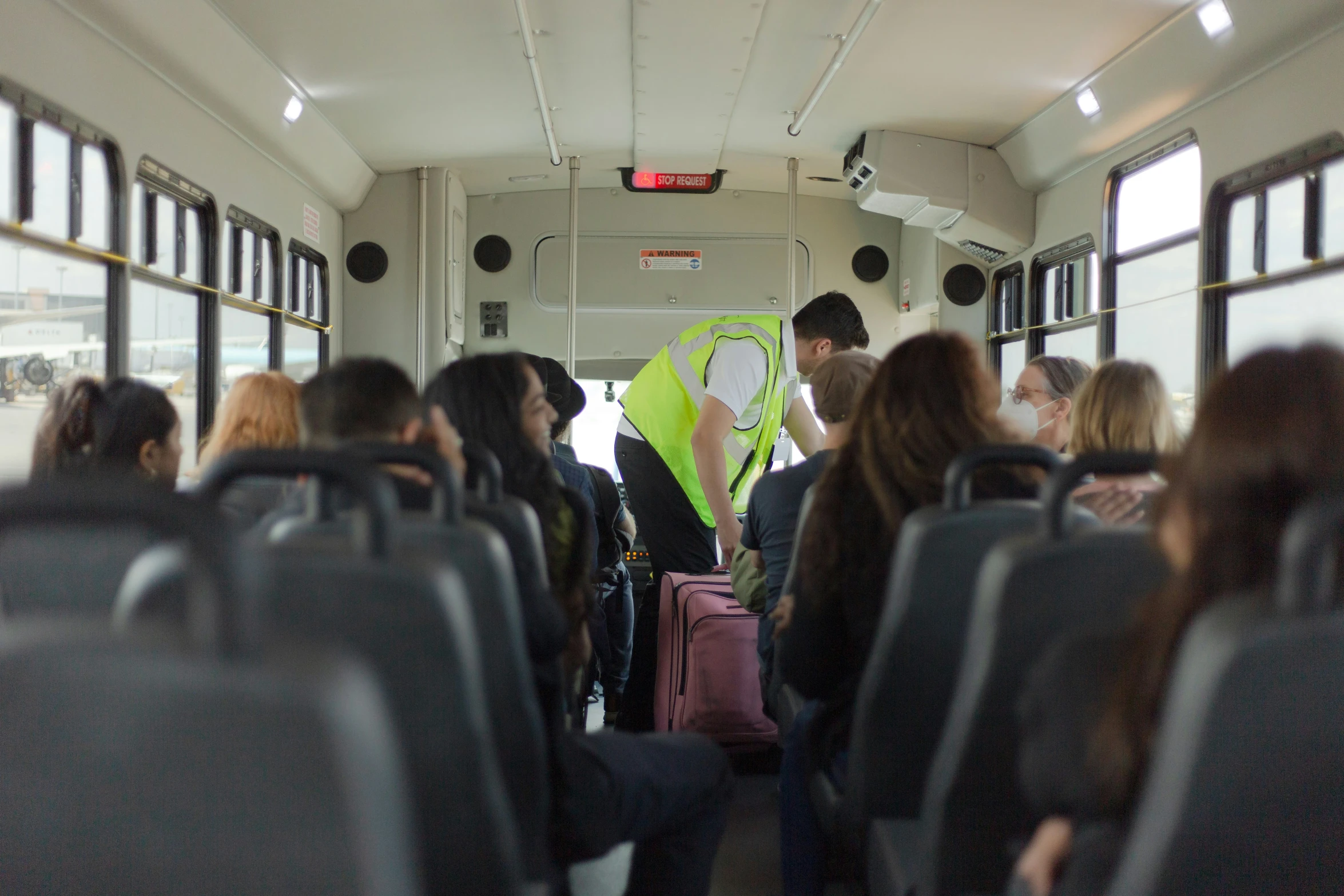 several people standing inside of a bus with their bags