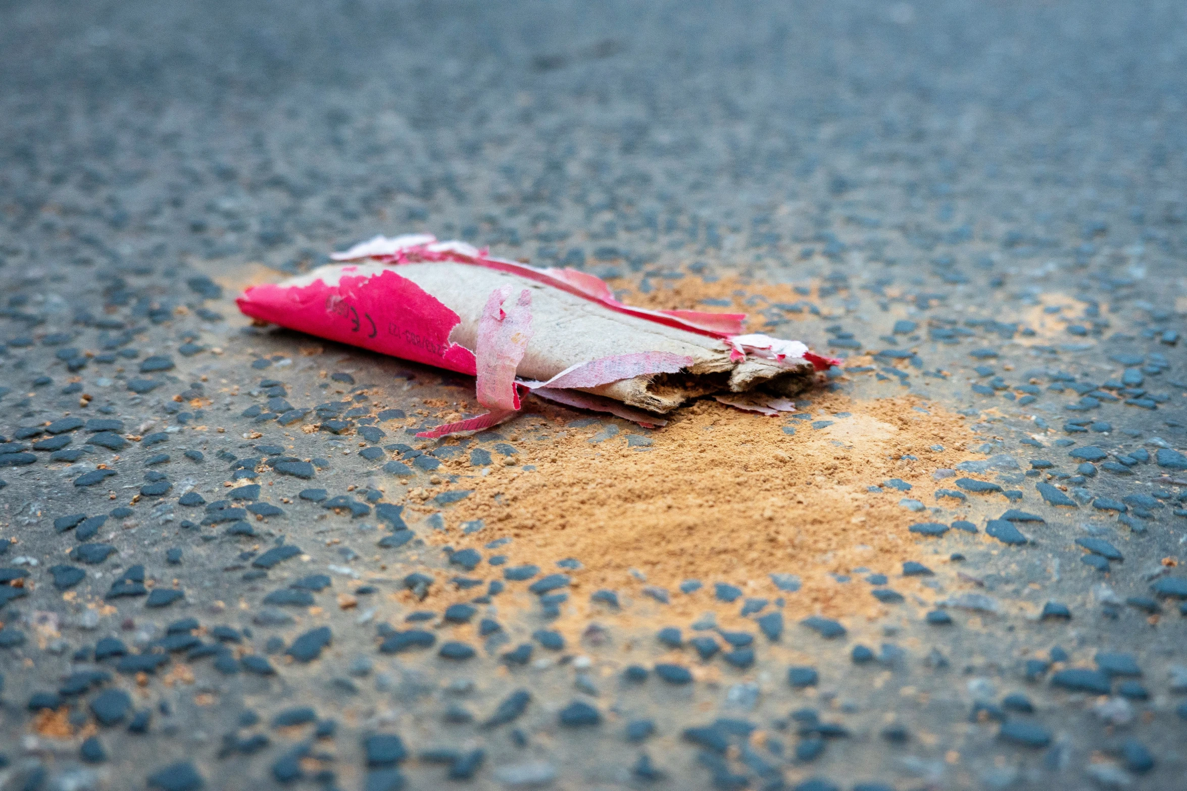 a pink and white piece of candy sitting on the ground