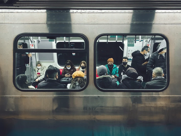 people riding in a subway car, with one passengers on the side