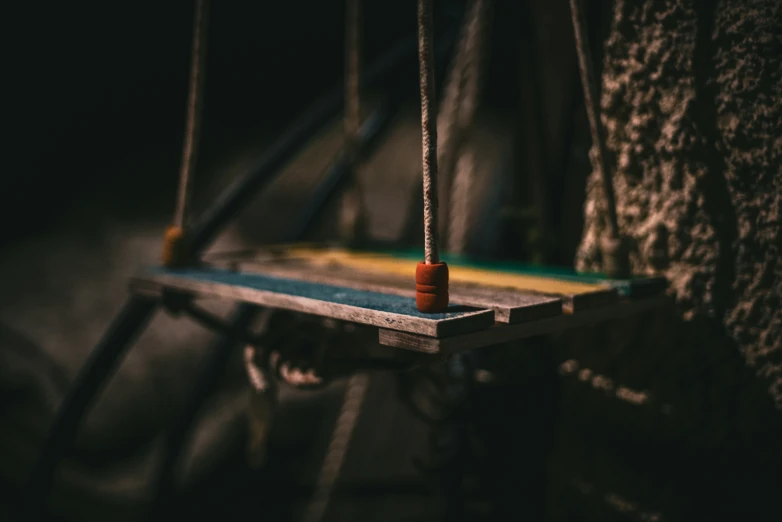 a wooden and string piece hanging from a tree