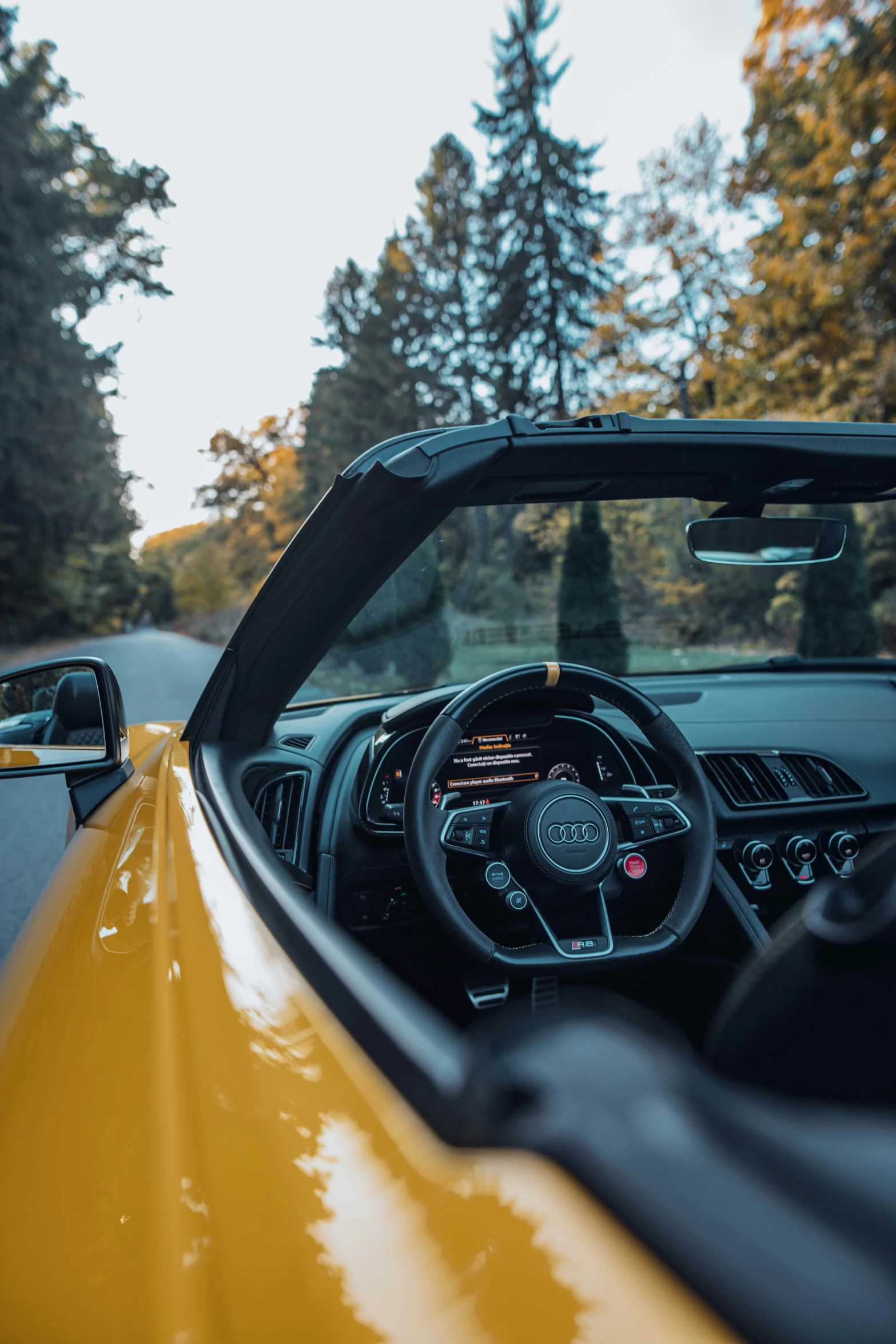 the interior of a yellow car looking out at a forest