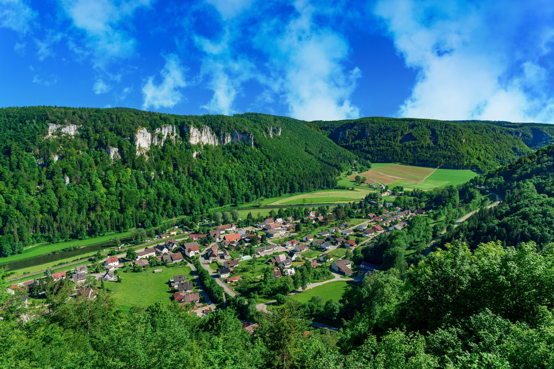 a view of an area surrounded by trees, mountains and buildings