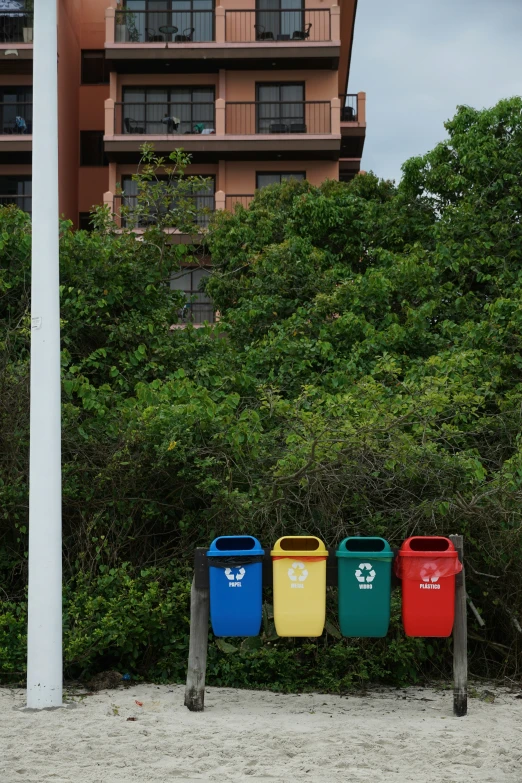 three trash cans placed beside a white pole