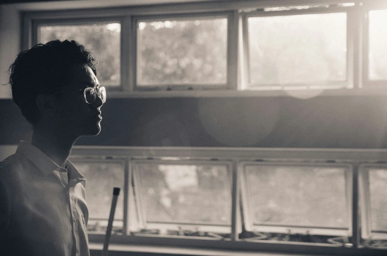 a man standing in front of a window while wearing sunglasses