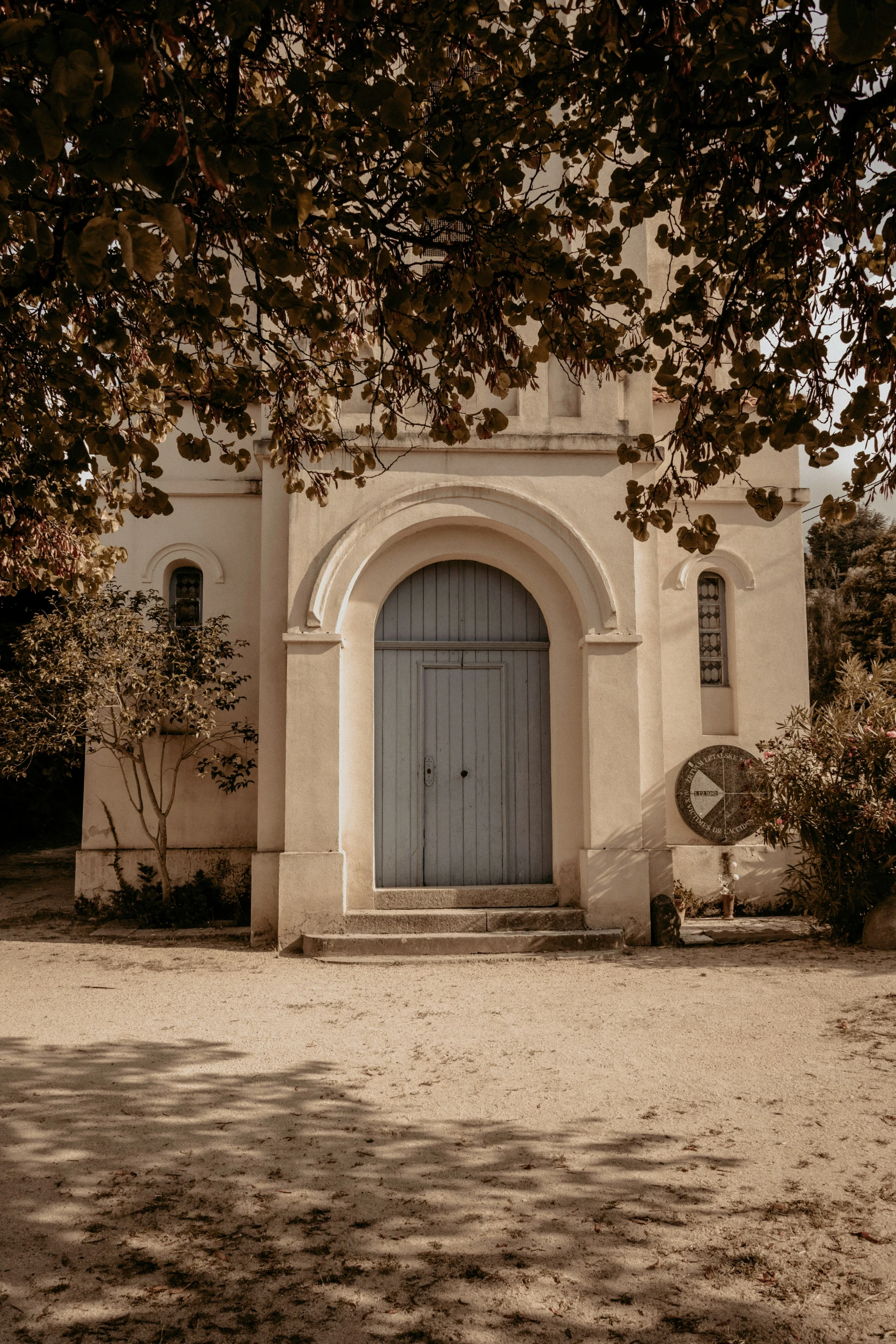 a small white and beige building sitting next to a tree