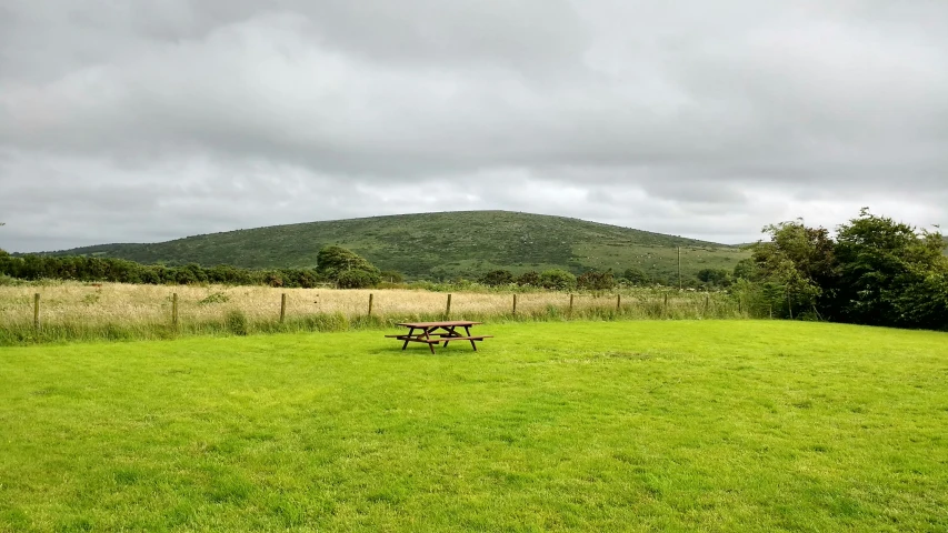 a picnic table is placed in the middle of a grassy field