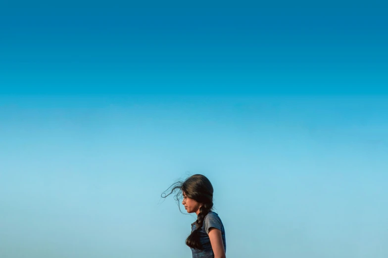 girl standing alone on sandy beach on sunny day