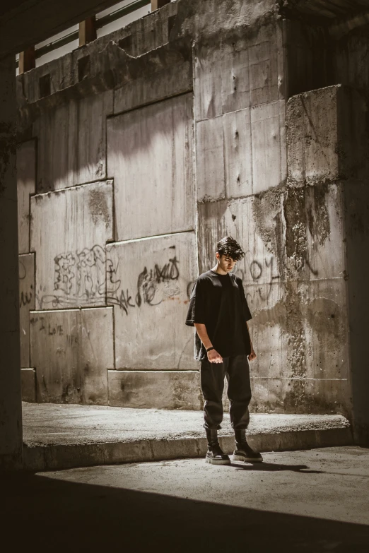 a young skateboarder stands by the edge of a concrete structure