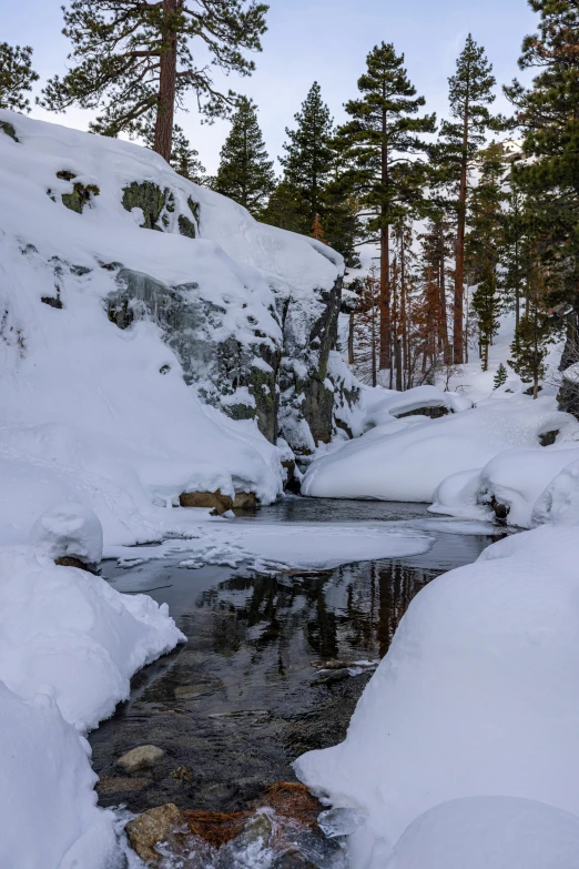 there is a small river that runs between the snow covered rocks