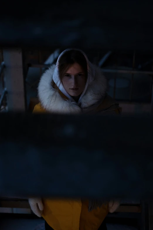 a woman in a yellow coat with a hood on sitting down