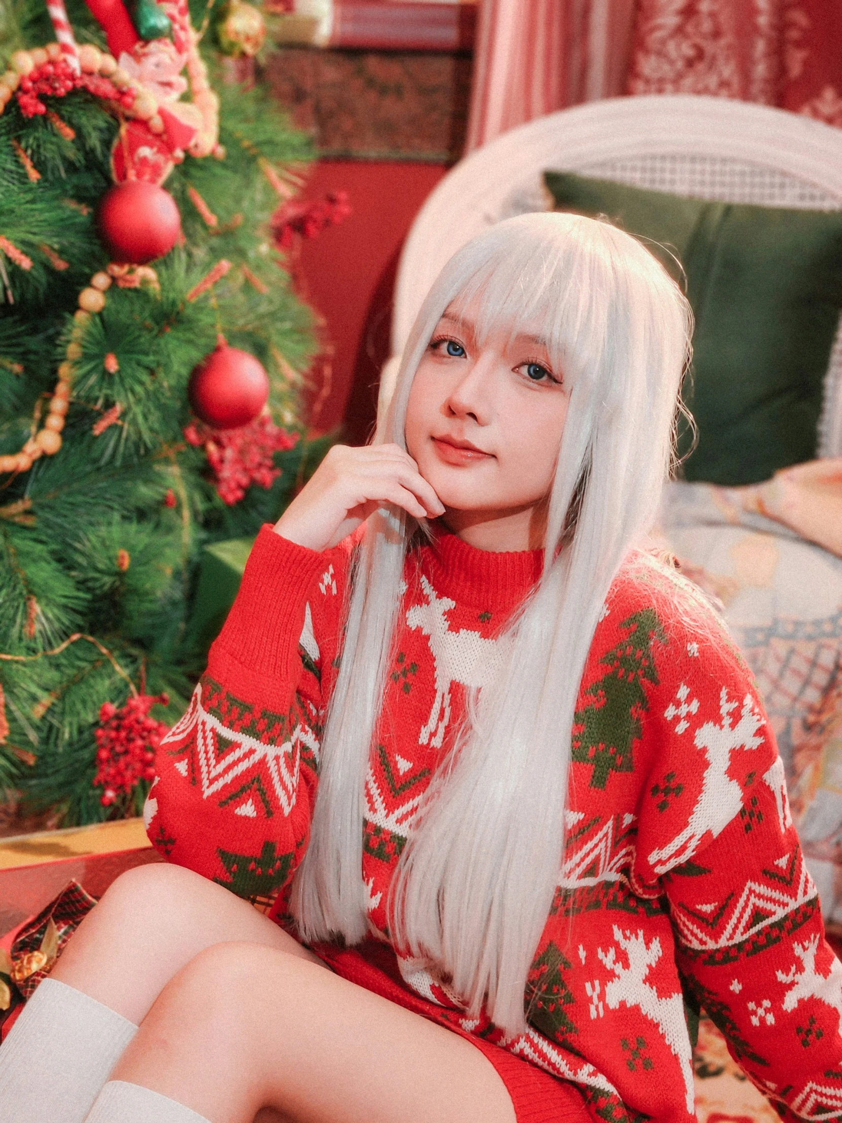 a woman sitting on a bed next to a christmas tree