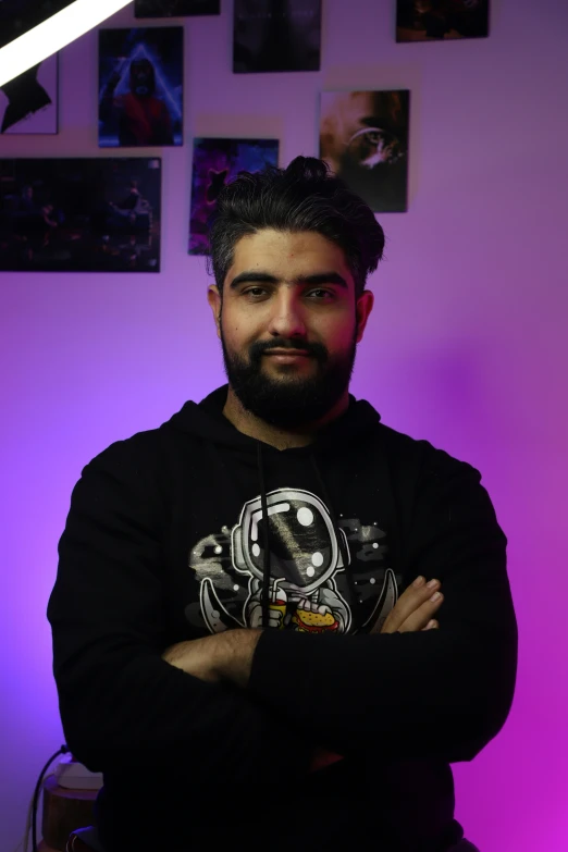 a man stands in front of a purple wall with posters on it