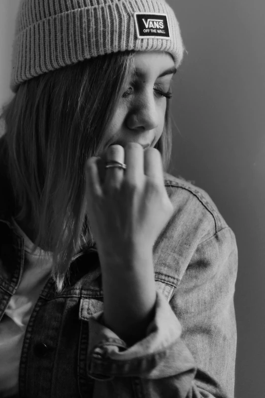 a young woman wearing a beanie smiles with her finger in her mouth