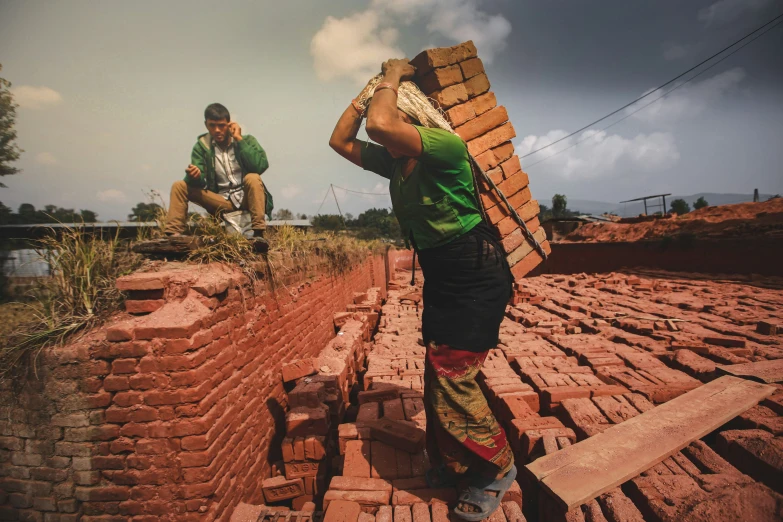 two men stand in the field with bricks piled on each other