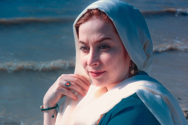 a woman is standing on a beach looking into the camera