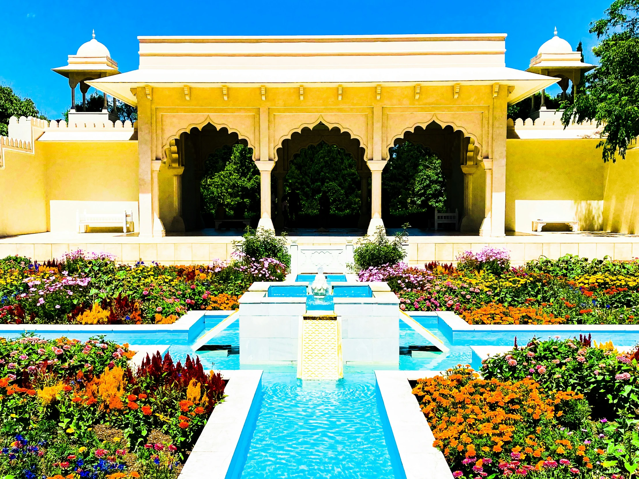 a park with many flowers and plants by a well lit pool