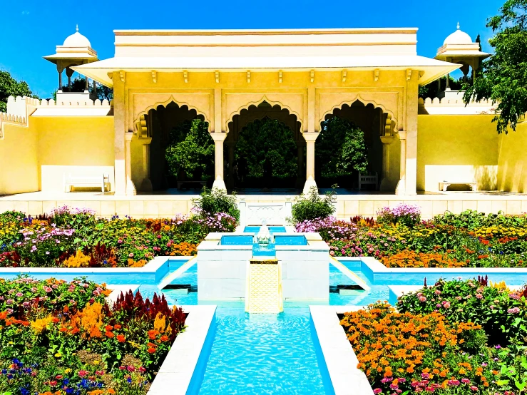 a park with many flowers and plants by a well lit pool