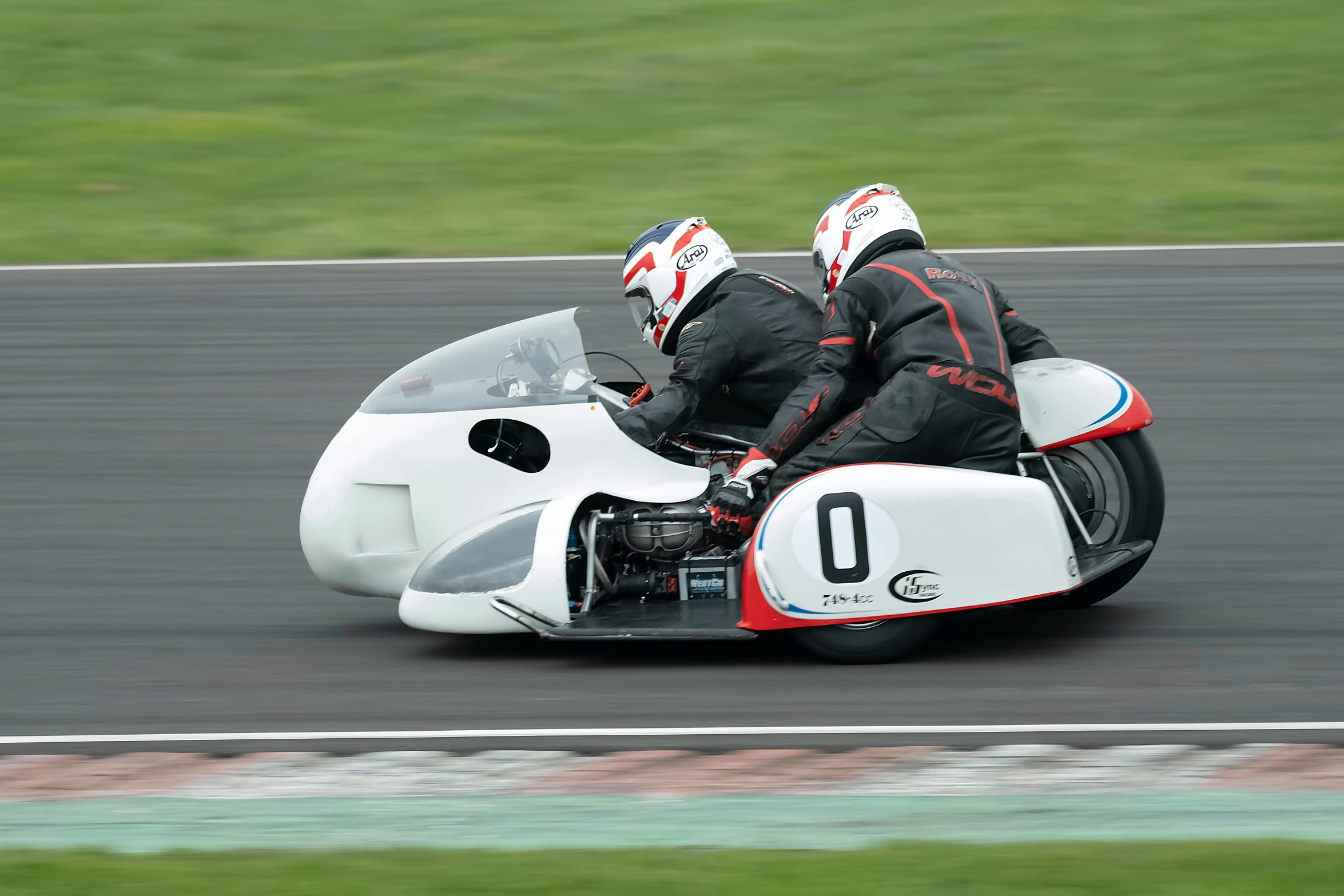 two people on a motorcycle riding around a track