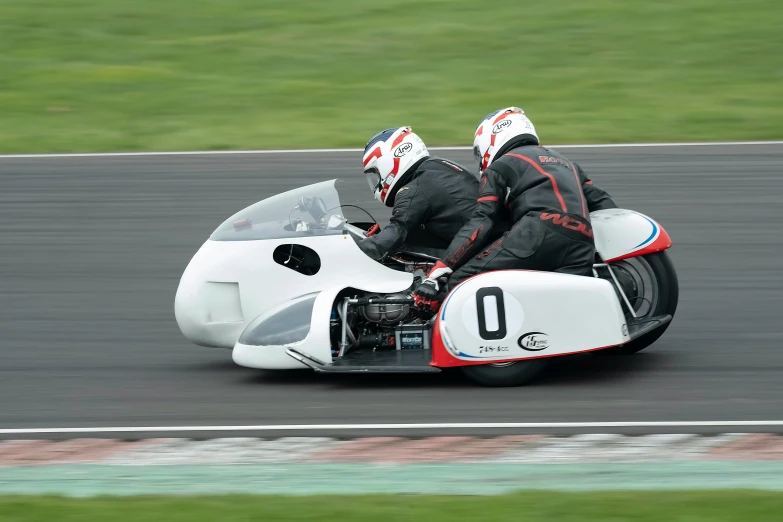 two people on a motorcycle riding around a track