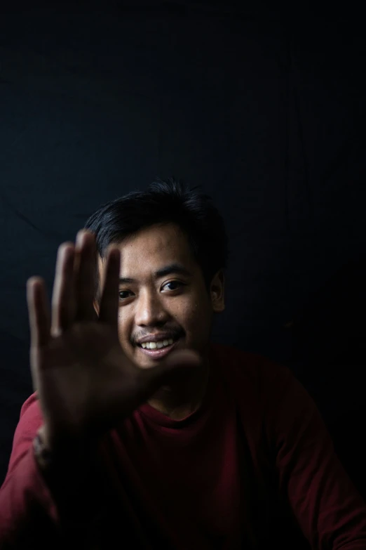 a man standing up and smiling while making the vulcan sign