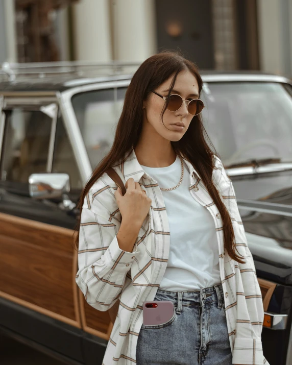 a woman standing in front of a car holding onto a purse