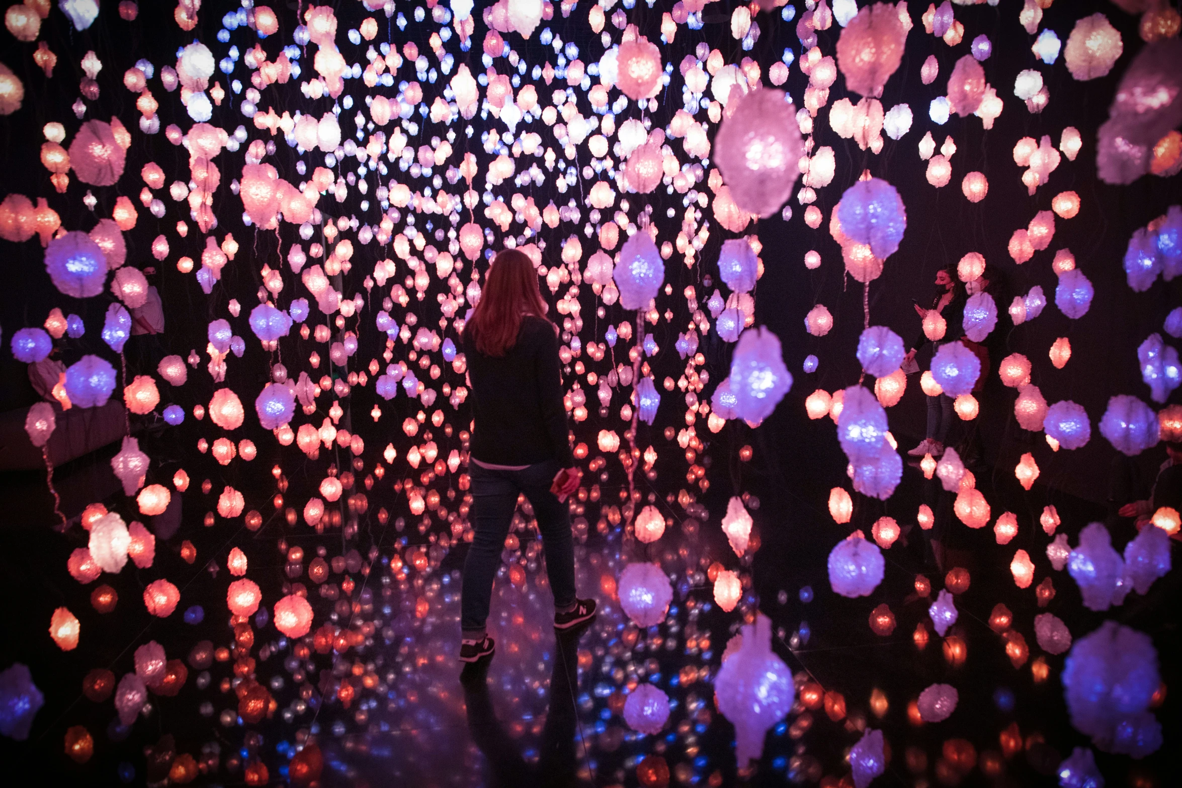 the woman is standing in the middle of the tunnel of balloons