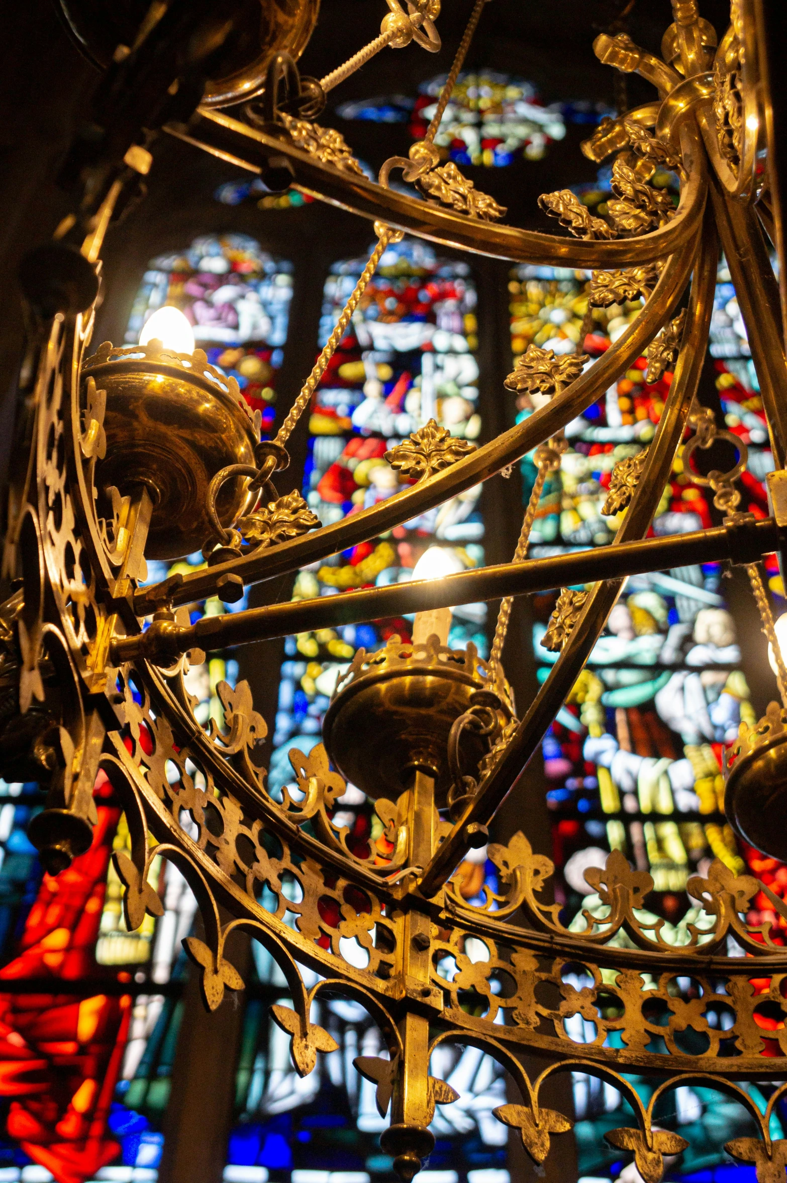 a small metal chandelier next to an ornate stained glass window