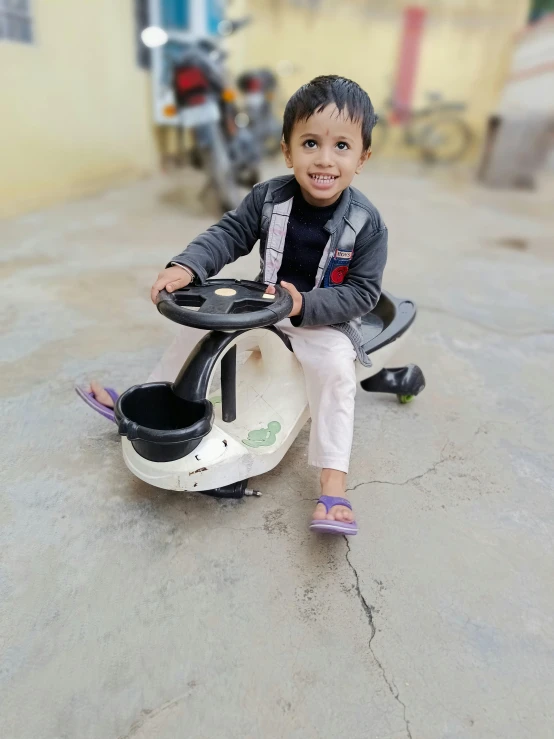 a child rides a toy motorcycle on the pavement