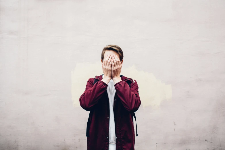 a person covering his face with both hands