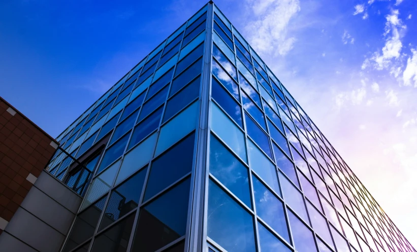 a large glass building under a blue cloudy sky