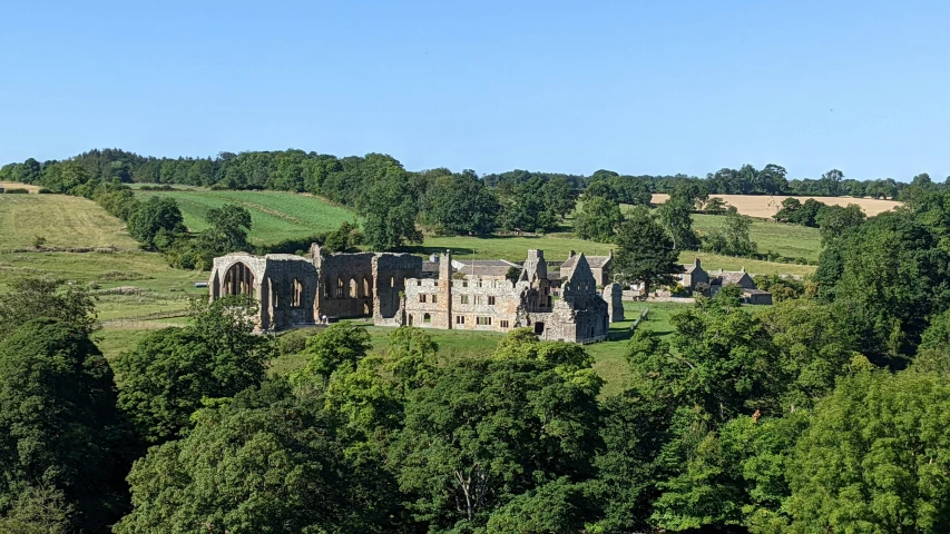 a castle like structure sits surrounded by lush green trees