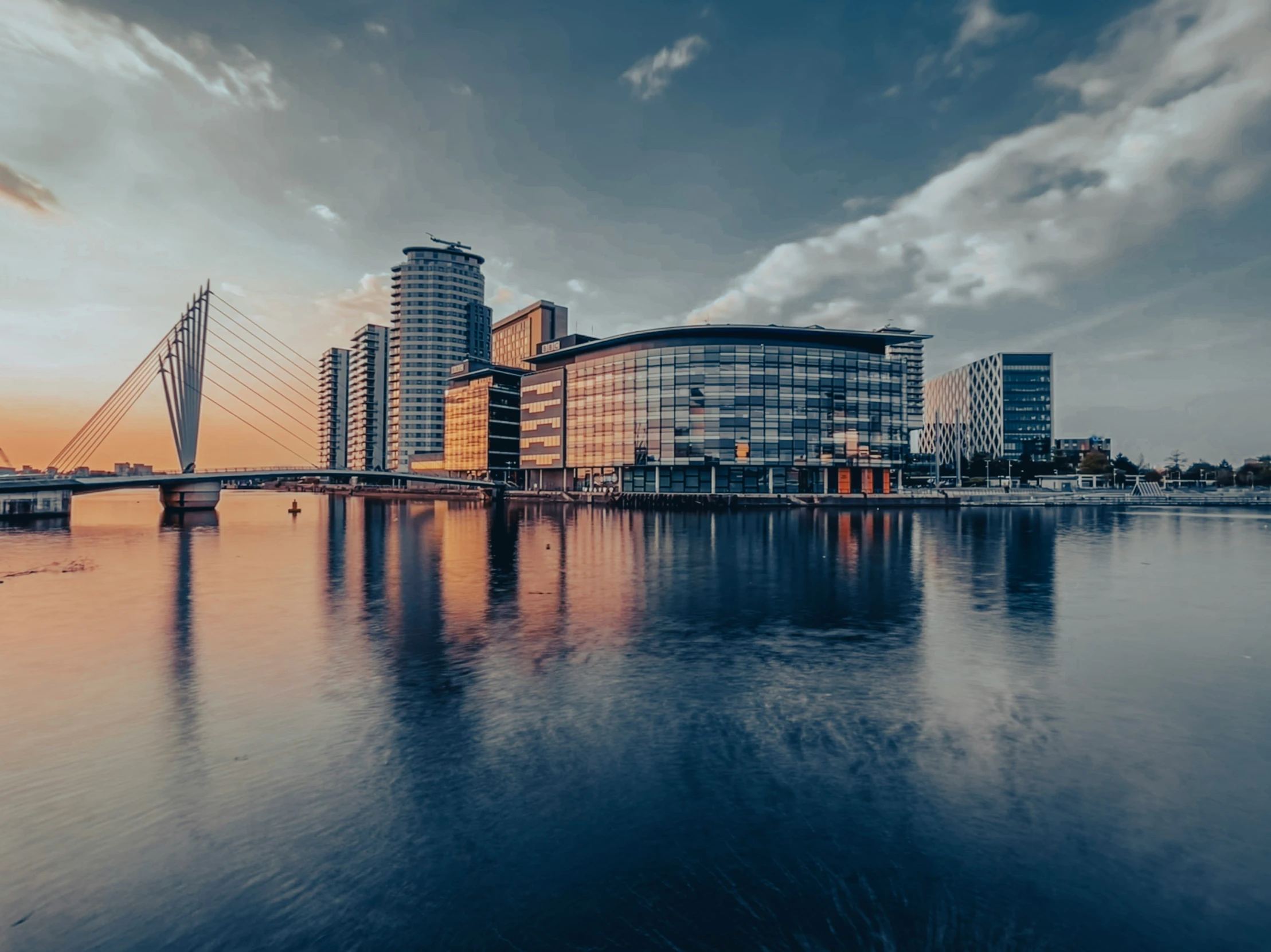 a view of some buildings and water with a bridge in the background