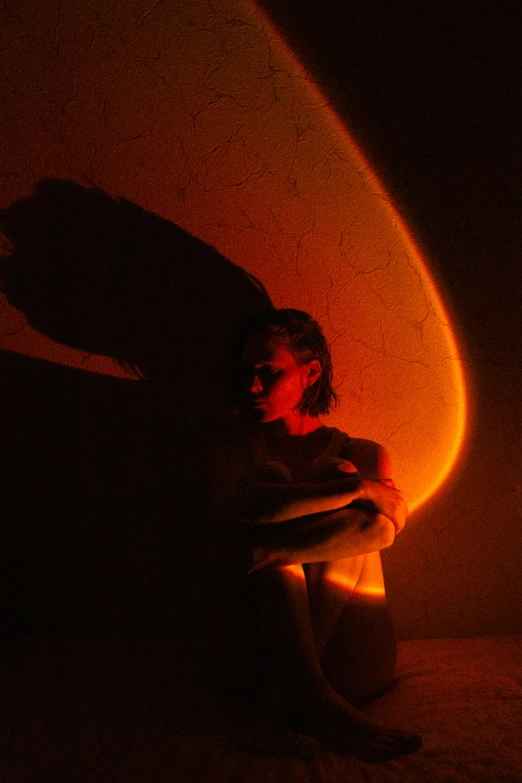 girl in the dark, sitting under a round lamp