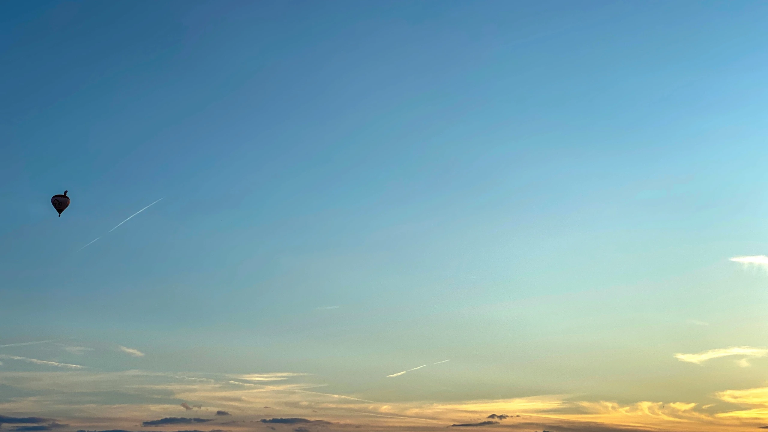 a kite flies through the sky during sunset