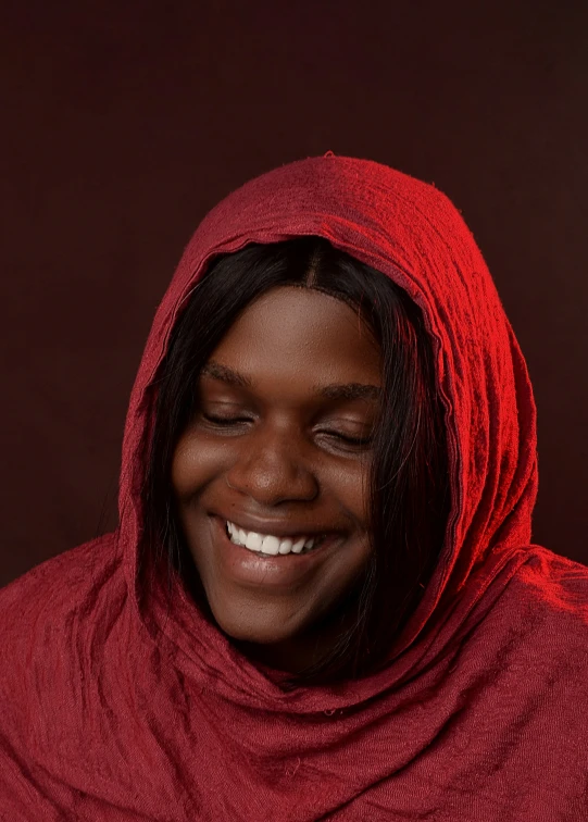 a smiling woman with red hood on, she is wearing a red shawl