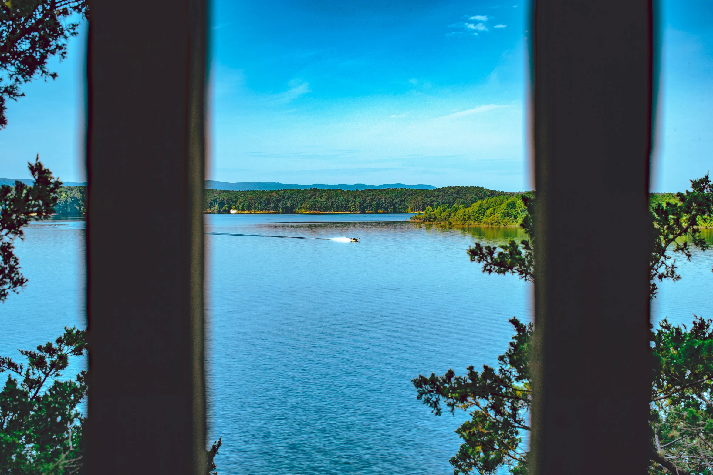 a lake seen from a window with a boat in it