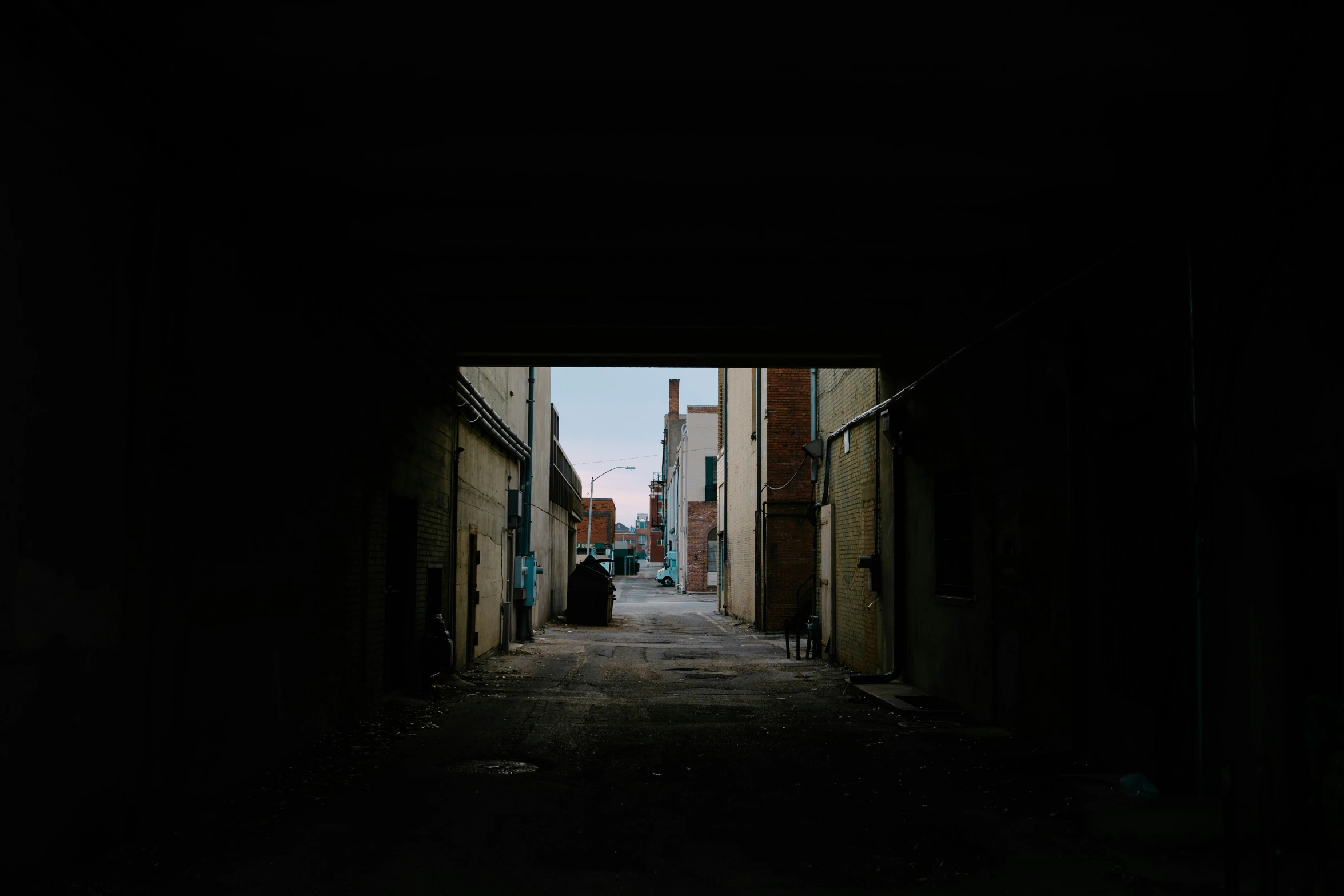 silhouette of person sitting on chair in dark alley