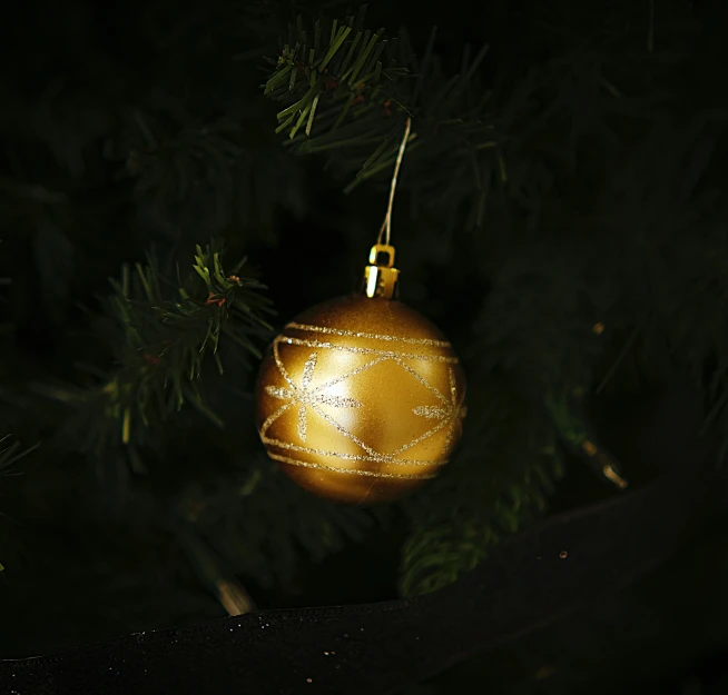 golden bauble hangs from the christmas tree