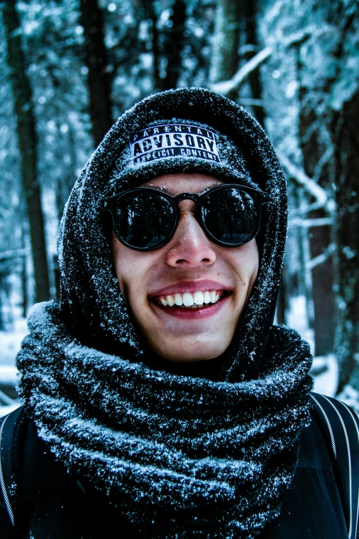 a man wearing sunglasses, scarf and hat in the snow