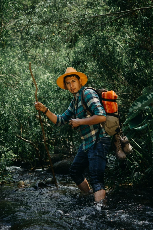 a man carrying a stick walking across a stream