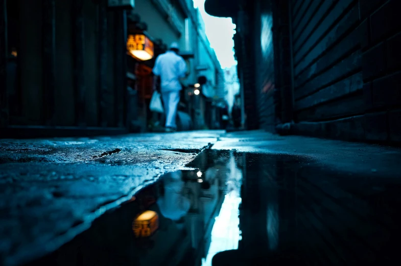 an empty sidewalk on a rainy night with the person walking up the street