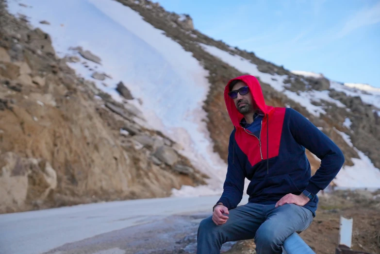 the man in the blue jacket is sitting on the side of the road