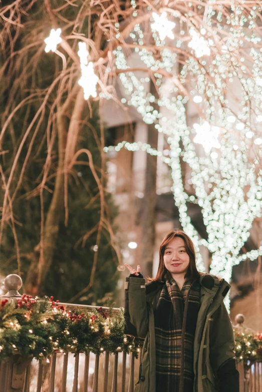 a woman posing in front of a lighted tree