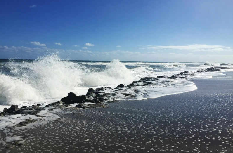 a large wave breaking on a shore with rocks