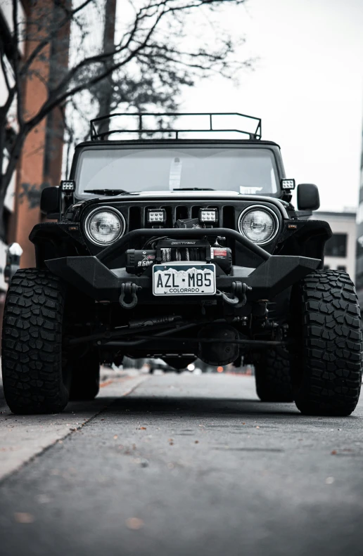 a black jeep driving down the road in front of a brick building