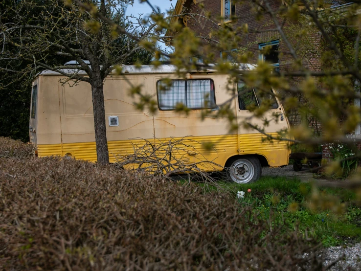 a yellow camper parked next to a tree