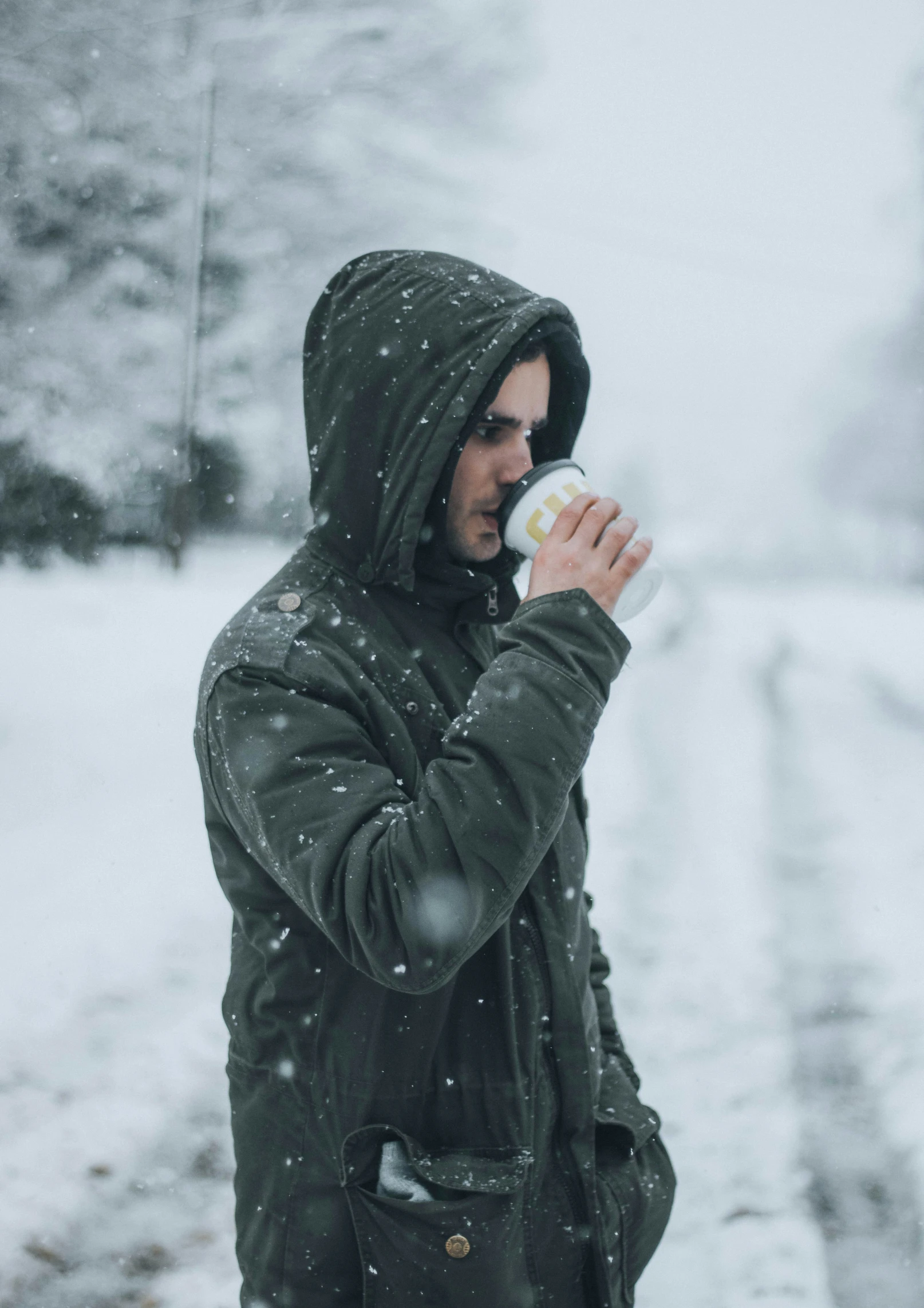 the man is drinking from the bottle in the snow