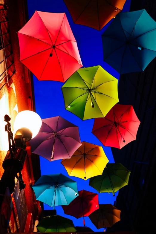 multicolored umbrellas hanging from the ceiling at a bar